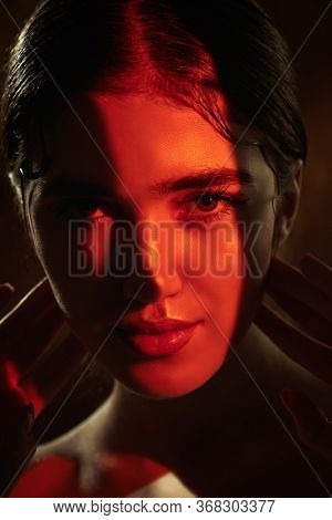 Portrait of a beautiful girl with shiny make-up and red arrows on her eyes in red light. Make-up and cosmetics concept. Beauty, fashion.