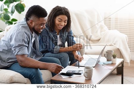 Household Budget. Smiling Black Couple Discussing Total Amount Of Their Spends At Home, Happy About 
