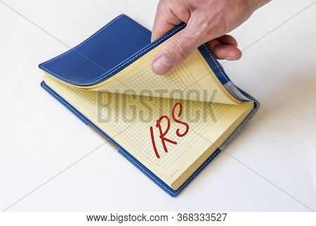 Irs Acronym Text Written On A Notebook Or Planner. Male Hand Opening A Planner With Irs Text. Tax Re