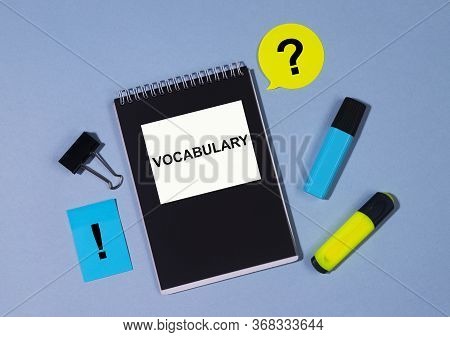 Vocabulary Text Word On White And Black Notebook With Clips Markers And Notes On Blue Table. Educati