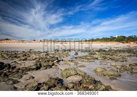 Western Australia - coast line at Dampier Peninsula with rocky coastline and a lighthouse at low tide and cliffs in morning light 