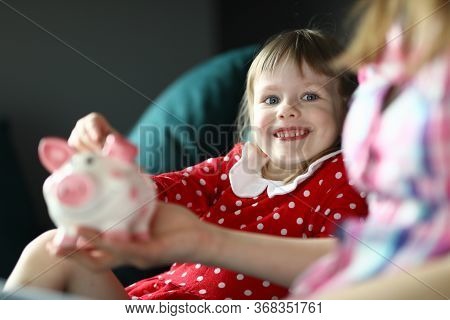 Portrait Of Smiling Attractive Funny Toddler Holding On Couch Indoors. Cute Kid Saving Up For Future