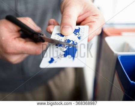 Male Hand Cutting Banking Card With Scissors Closeup