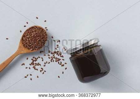 Vegan Organic Paste Of Flax Seeds In Glass Jar And Flax Seeds In Spoon On Light Blue Background, Urb
