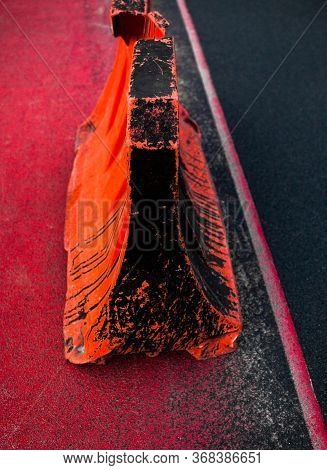 Orange Dirty Safety Barrier On The Road. Red Painted Asphalt. Red Road Surface Marking.