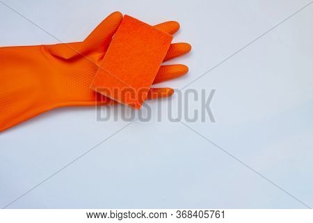 Orange Glove For Cleaning With An Orange Wisp On A Light Background With A Copy Space