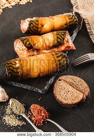 Appetizing Smoked Mackerel Fish Rolls With Spices, Pepper And Bread On Dark Slate Background. Medite