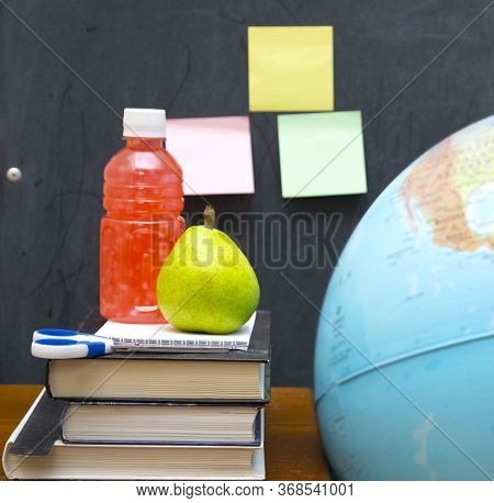 Juice And Pear On Top Of A Stack Of Textbooks. Lunch Breakin School.