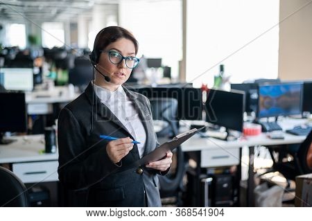 Serious Business Woman In A Suit Answers The Customers Call On The Headset. Female Manager Takes Not