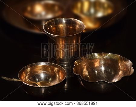 Empty Glass And Bowls Of Brass Isolated In Dark Background. Brass Is Also Called As Peetal In Hindi 