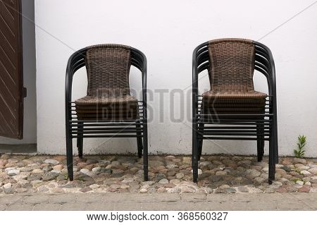 There Are No Visitors In The Street Cafe, The Restaurant Is Closed. Wicker Chairs Stacked On Top Of 