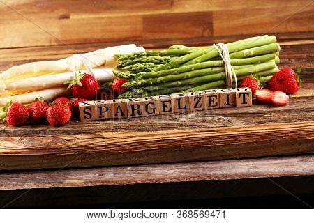 White And Green Asparagus And Strawberries On Background With The German Word Spargelzeit In Wooden