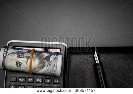 calculator and a roll of us dollarts on desk.