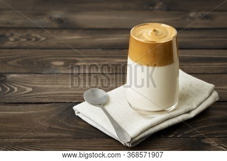 Dalgon Coffee On A Brown Wooden Background. Trendy Korean Drink. Cold Coffee. Whipped Coffee. A Plac