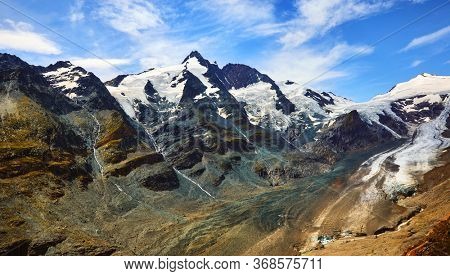Panoramic view at Pasterze Glacier Grossglockner among austrian Alps mountains summits blue sky clouds.