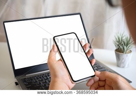 Mockup Hand Holding Blank White Screen Smartphone With Blank White  Laptop Screen On Home Office Wor