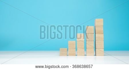 Wooden Blocks As A Pyramid Staircase On Blue Background. Success, Growth, Win, Victory, Development 