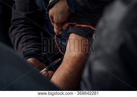 Two Shabby Men Preparing Drug Injection In Slums.