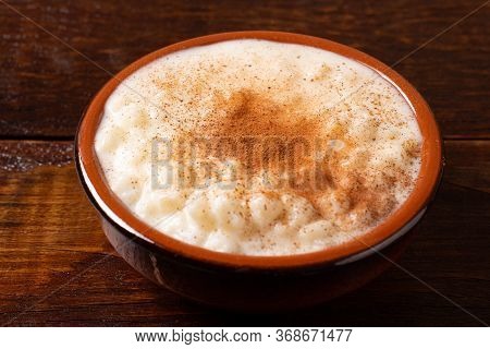 White Corn Cooked With Milk Known As Canjica, Canjicão Or Mungunza, In A Rustic Bowl On Wooden Table