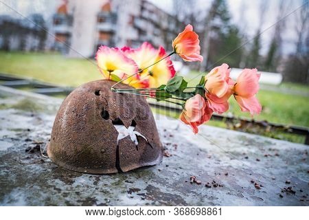 Old Broken Military Helmet With Flowers. Day Of Memory. Soldiers Helmet Of A Warrior Of The Ussr Wit