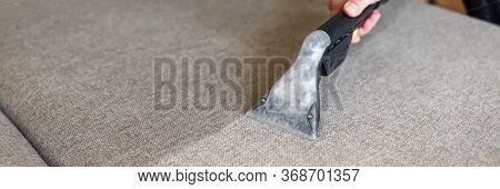 Close-up Of Housekeeper Hand Holding Modern Washing Vacuum Cleaner And Cleaning Dirty Sofa With Prof