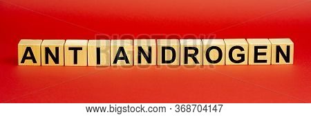 The Word Antiandrogen Is Written On Wooden Cubes On A Red Background. The Concept Of Hormonal Disord