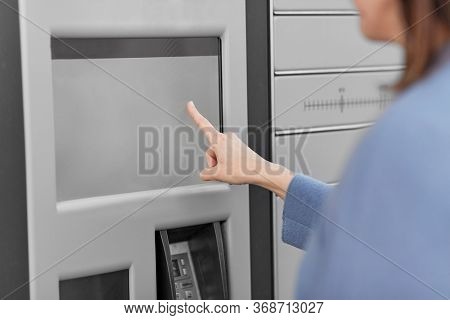 mail delivery and post service concept - close up of woman choosing operation on outdoor automated parcel machine's touch screen