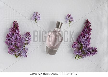 Glass, Perfume, Cosmetic Bottle On White Background With Water And Lilac. Top View, Closeup