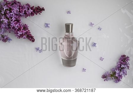 Glass, Perfume, Cosmetic Bottle On White Background With Water And Lilac. Top View, Closeup