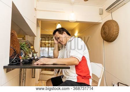 Matured Asian Business Man With Hand On Forehead In Stressful Expression In Work From Home Video Con
