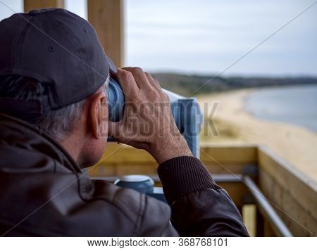 Man Looking Through Tourist Binoculars. Hands On The Telescope. Ocean On The Background. Vacation Co