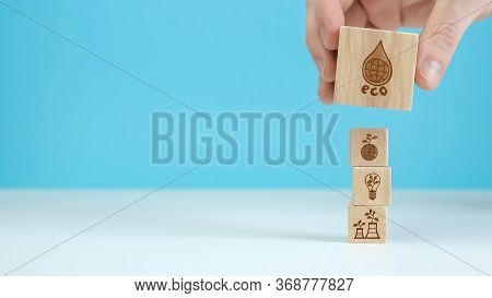 Wooden Blocks With Environmental Symbols Arranged A Man Is Holding The Top One. Ecology