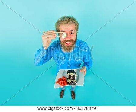 Exotic Nutrition. Seafood. Man Eating Sushi. Man Hold Piece Sushiroll In Front Of Eye. Man With Sush