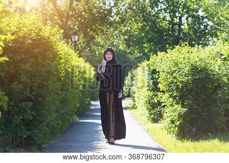 Beautiful Confident Running Muslim Woman. A Girl In Islamic Oriental Clothes Beautifully Walks Along