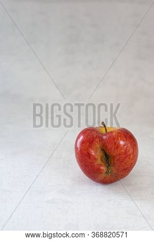 Red Organic Ugly Apple On Grey Cement Background With Copy Space. Fruit With Unusual Shape. Buying I