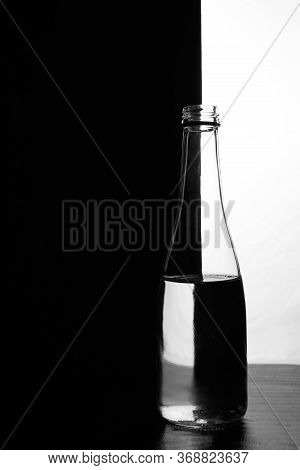 A Bottle Of Water On A Black And White Background. Optical Over-reflection Effect