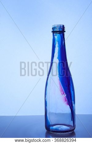 Glass Bottle With Blue Red Inside Stands On A Light Background