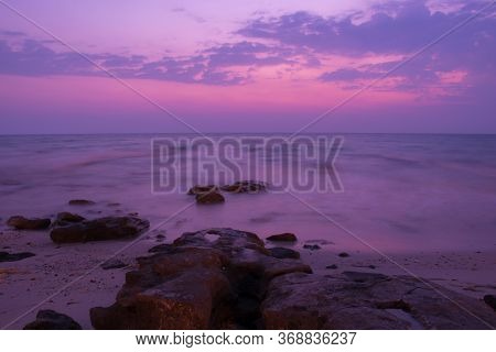 Peaceful View Of Stones In Seaside At Early Morning Purplish Lighting Sunrise In Kuwait Beach.