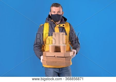 Young Caucasian Food Delivery Man In Protective Black Mask And Gloves Against Virus And Bacteria Is 