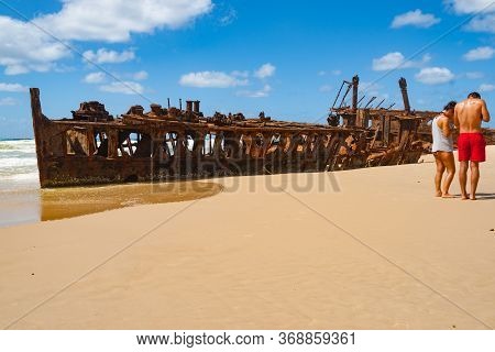 Fraser Island Australia - March 13 2014; Two Tourists On Beach By  Maheno Shipwreck Rusting Away On 