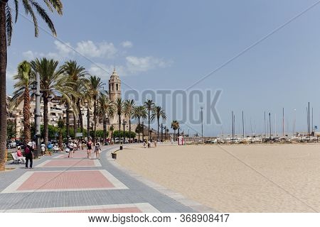 Barcelona, Spain - April 30, 2020: People Walking On Sidewalk Near Palm Trees And Church Of Saint Ba