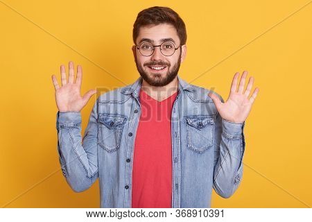Horizontal Shot Of Happy Joyful Funny Guy Having Beard, Raising Arms, Making Gesture, Looking Direct