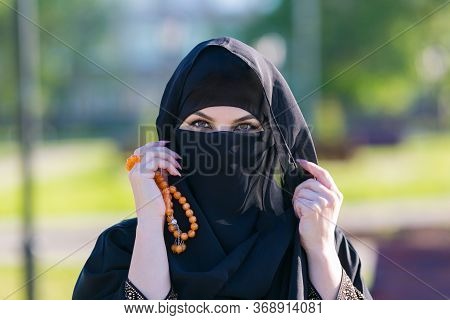 Muslim Woman Stands With Rosary Islamic Scores. Islamic Woman In National Women's Clothing Holds Rel