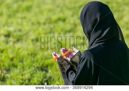 Islamic Woman Prayer In A City Park. Islamic Woman, Performs Morning Prayer Sitting On Green Grass I