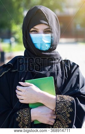Muslim Woman Stands With A Quran In Her Hands. An Islamic Woman In National Women Clothing Holds Hol