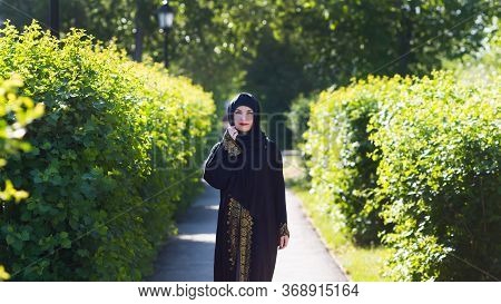 Beautiful Confident Running Muslim Woman. A Girl In Islamic Oriental Clothes Beautifully Walks Along