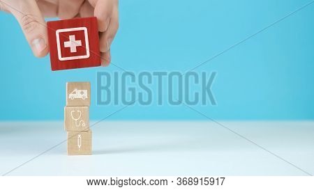 Wooden Blocks With The Healthcare Medical Symbol Arranged A Man Is Holding The Top One.