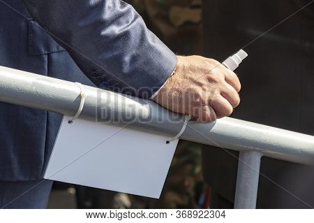Daylight. A Metal Railing Rests On Her Male Hand. It Has An Antiseptic In A Small Bottle.