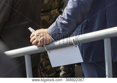 Daylight. A Metal Railing Rests On Her Male Hand. It Has An Antiseptic In A Small Bottle.