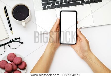 Mock Up Image Of Female Hand Holding And Using Black Mobile Phone With Blank Screen On Laptop Comput